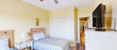 A hotel room with two beds, a ceiling fan, a TV, and a white wardrobe.