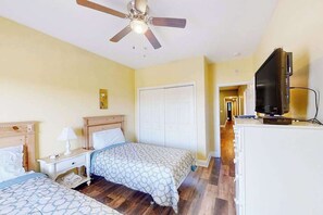A hotel room with two beds, a ceiling fan, a TV, and a white wardrobe. - Coconut Grove Unit 405 (North Myrtle Beach)