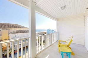 A balcony with a view of the beach and houses, featuring two yellow Adirondack chairs. - Coconut Grove Unit 405 (North Myrtle Beach)