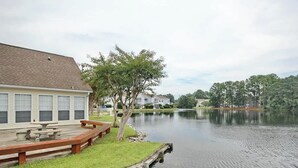 A lakeside property with a dock, picnic table, and a building with large windows. - Home Away From Home Unit J (Surfside Beach)
