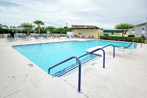A swimming pool with a blue waterline, surrounded by lounge chairs and a small building. - Home Away From Home Unit J (Surfside Beach)