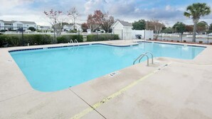 A rectangular swimming pool with a blue interior, surrounded by a concrete deck with yellow lines marking the edges. - Home Away From Home Unit J (Surfside Beach)