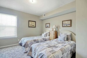 A bedroom with two beds, a dresser, and a window with blinds. - Home Away From Home Unit J (Surfside Beach)