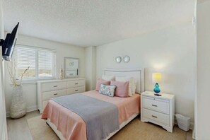 Une chambre à coucher avec un lit, des tables de chevet, une lampe, une fenêtre et une horloge murale.