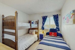 A bedroom with bunk beds, a bedside table with a lamp, and nautical-themed decor. - The Pinnacle Unit 601 (North Myrtle Beach)