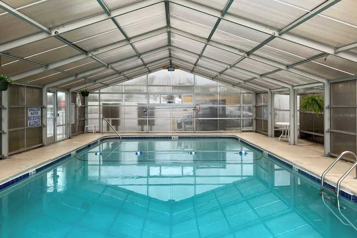 A swimming pool with a glass enclosure, metal railings, and a sign indicating shallow water no diving.