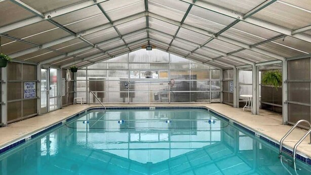 En swimmingpool med en glasvägg, metallräcken och en skylt som visar att vattnet är grunt och att man inte får dyka.