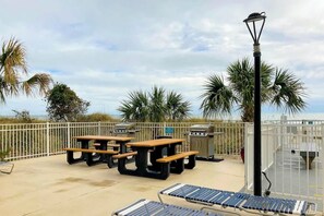 Eine Terrassenanlage im Freien mit Picknicktischen, Grillanlagen und einer Laterne.