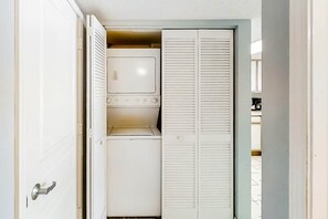 Ein kleiner Hauswirtschaftsraum mit Waschmaschine, Trockner und Stauraumschränken.