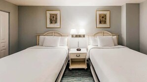 A hotel room with two beds, a nightstand, a lamp, and framed artwork on the wall. - Bay Watch Resort 0411 (North Myrtle Beach)