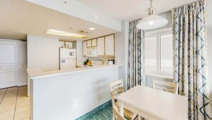 A compact kitchen with white cabinets, a microwave, and a small island with a sink. - Bay Watch Resort 0411 (North Myrtle Beach)