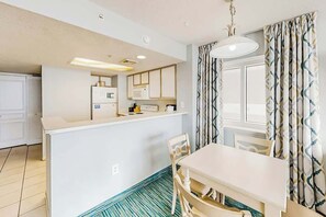 A compact kitchen with white cabinets, a microwave, and a small island with a sink. - Bay Watch Resort 0411 (North Myrtle Beach)