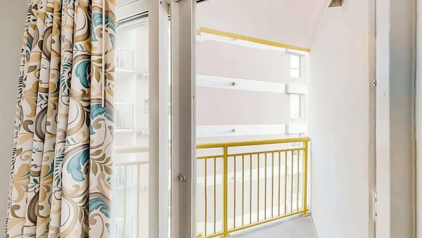 A corridor with a view of a balcony with yellow railings. - Bay Watch Resort 0411 (North Myrtle Beach)
