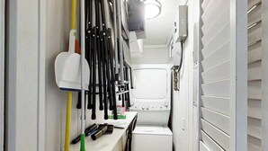 Una sala de bugaderia amb una rentadora, un tendal i diferents eines de neteja.