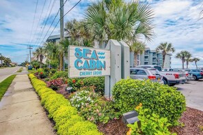 Schild für Sea Cabin in Cherry Grove, mit einem Parkplatz und Palmen im Hintergrund.