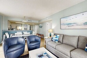 Un salon moderne comprenant un canapé, deux fauteuils, une table basse et un tableau représentant des oiseaux, accroché au mur.