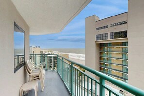 Ein Balkon mit Blick auf Strand und Meer, ausgestattet mit Geländer und einigen Stühlen.
