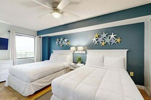 Une chambre d’hôtel avec deux lits, un ventilateur de plafond, une fenêtre avec des rideaux et des éléments de décoration murale.