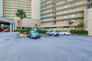 Ein mehrstöckiges Hotel mit Parkplatz und mehreren parkenden Autos.