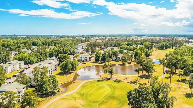 Golfkenttä, jossa on lampi, ja jota ympäröivät asuinrakennukset ja puut.