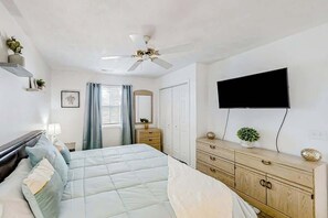 A bedroom with a bed, a ceiling fan, a dresser, a TV, and a window with curtains. - White River Unit 31i Condo (Myrtle Beach)