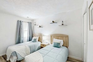 Ein Schlafzimmer mit zwei Betten, einem Nachttisch, einer Lampe und Wandregalen mit Dekoration.