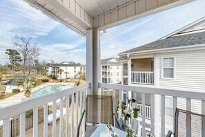 A balcony with a view of a swimming pool and adjacent buildings. - White River Unit 31i Condo (Myrtle Beach)