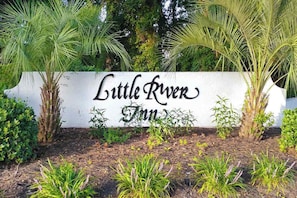 A sign for 'Little River Inn' surrounded by greenery and palm trees. - Beach Golfer's Nest Retreat (Little River)