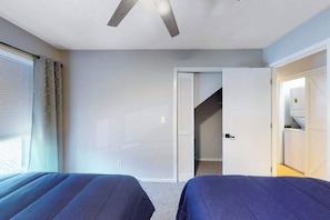 A room with two beds, a ceiling fan, a window with curtains, and a door leading to a staircase. - Beach Golfer's Nest Retreat (Little River)