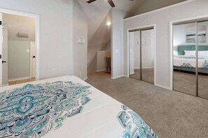 Ein Schlafzimmer mit einem großen Bett, einem begehbaren Kleiderschrank und einer Schiebetür zu einem weiteren Raum.