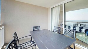 Ein Balkon mit Tisch und Stühlen, Blick auf das Meer und ein gemustertes Sofa.