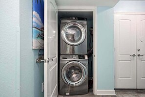 A laundry room with two stacked front-loading washing machines, a door with a handle, and a wall-mounted towel rack. - Prince Resort Unit 1834 (North Myrtle Beach)