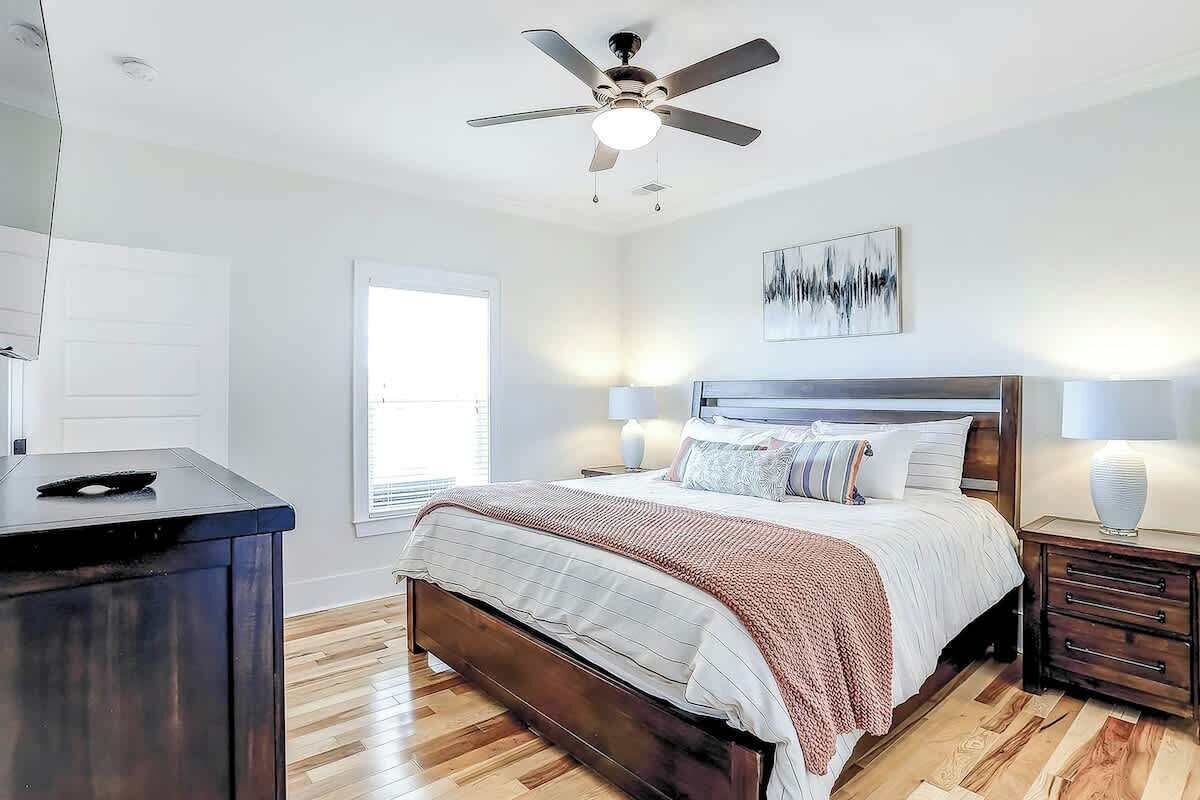 A bedroom with a bed, bedside lamps, a ceiling fan, and a window.