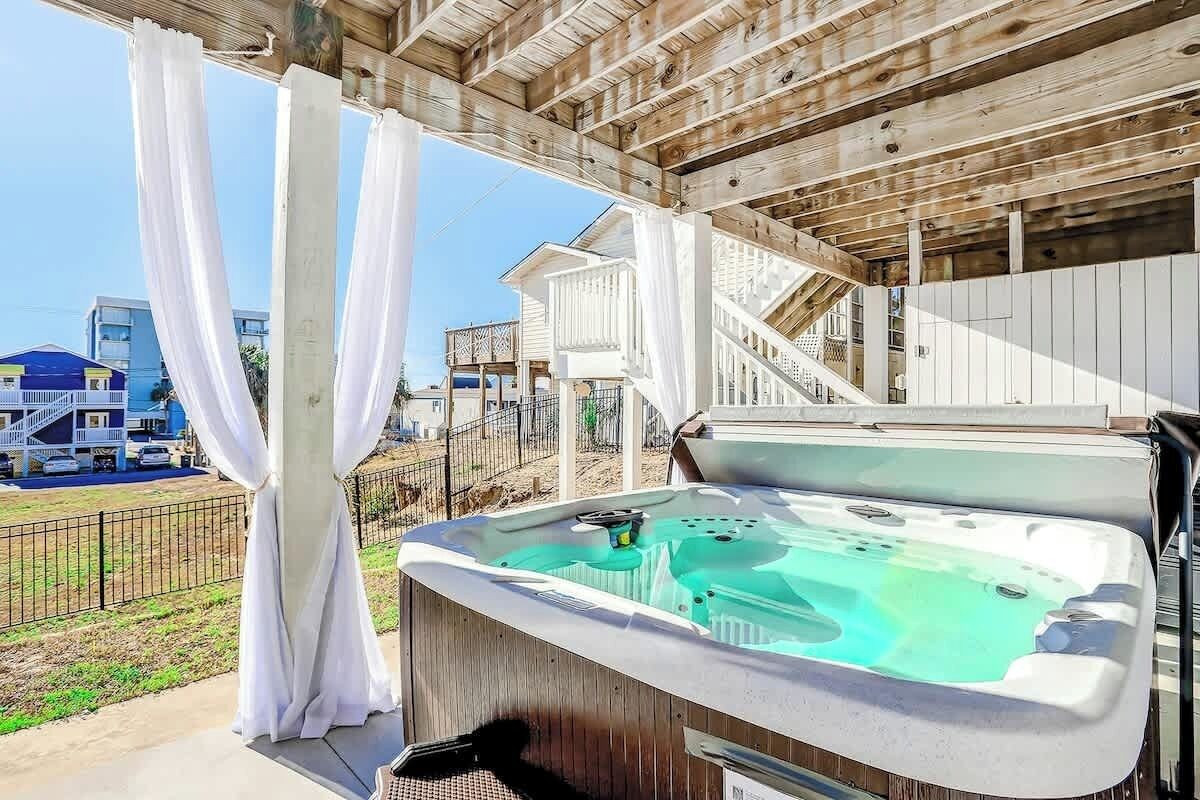 Uma banheira de hidromassagem sob um pérgola de madeira, com vista para uma área residencial.