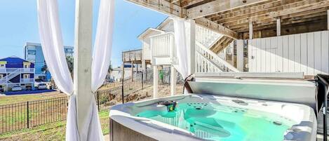 Uma banheira de hidromassagem sob um pérgola de madeira, com vista para uma área residencial.
