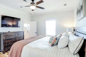 A bedroom with a bed, a ceiling fan, a dresser, and a television on the wall. - Strand Ave Estate Retreat (North Myrtle Beach)