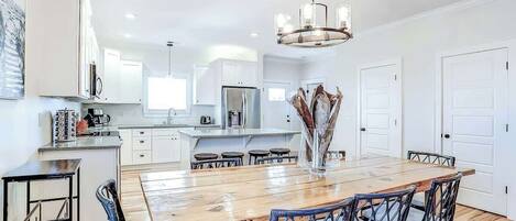 A modern kitchen with white cabinetry, a wooden dining table, and blue chairs.
