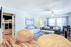 A room with a bunk bed, a sofa, a coffee table, and bean bags. - Strand Ave Estate Retreat (North Myrtle Beach)