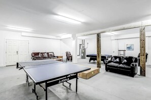 A spacious room with a ping pong table, a sofa, a pool table, and a billiards table. - Strand Ave Estate Retreat (North Myrtle Beach)