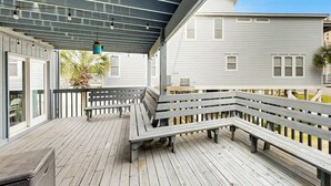 En overdækket terrasse med bænke, et bord og en hængende lampe.
