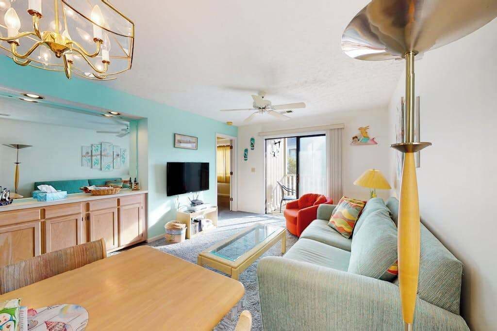 A modern living room with a dining area, a kitchen, and a balcony.