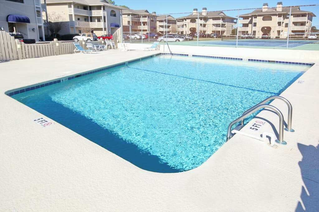 A rectangular swimming pool with a clear blue water surface, surrounded by a white deck.