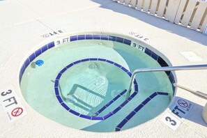 Uma banheira de hidromassagem circular com 90 centímetros de diâmetro, rodeada por uma borda de azulejos, e com placas indicando '3 FT' e 'SEM MEROULHO'.