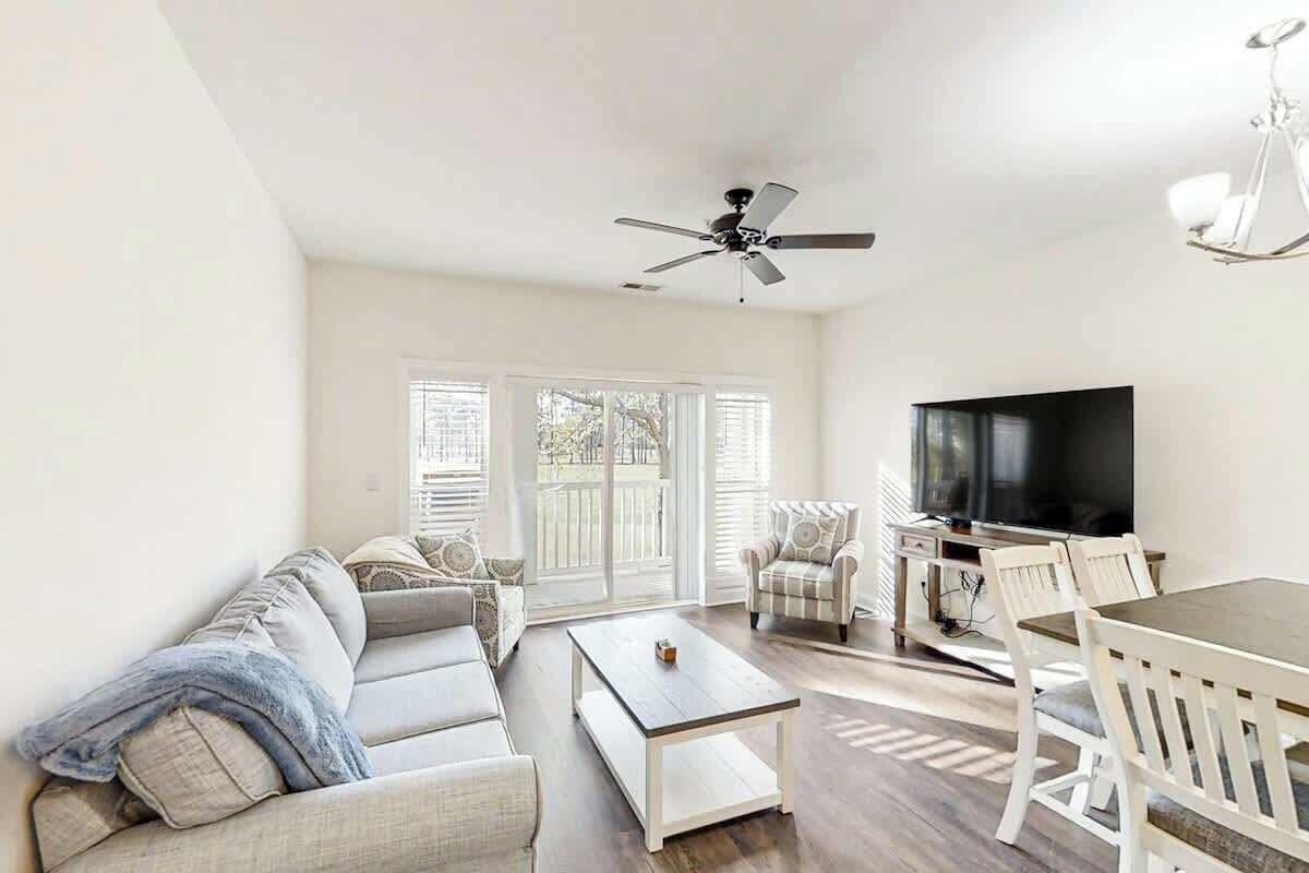 A living room with a sofa, a coffee table, a TV, and a dining table with chairs.