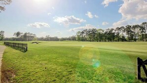 Um campo de golfe com céu claro, um caminho para pedestres e uma cerca.