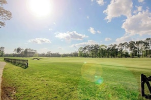 Ein Golfplatz mit blauem Himmel, einem Fußweg und einem Zaun.