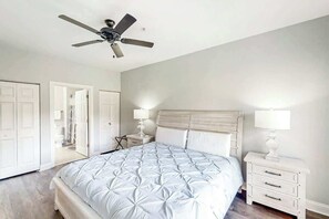 Ein Schlafzimmer mit einem Bett, einem Nachttisch, einem Deckenventilator und einer Tür.