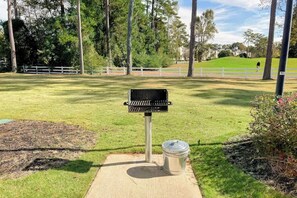 A park with a grill station, a trash can, and a white fence in the background. - World Tour Sawgrass 205 (Myrtle Beach)