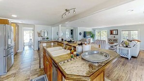 A spacious kitchen with a large island, modern appliances, and a view to the living area. - Lands End Beach Retreat (Murrells Inlet)