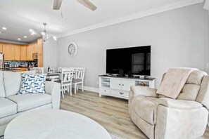 Ein modernes Wohnzimmer mit einer Couch, einem Fernseher und einem Essbereich mit Stühlen und einem Tisch.